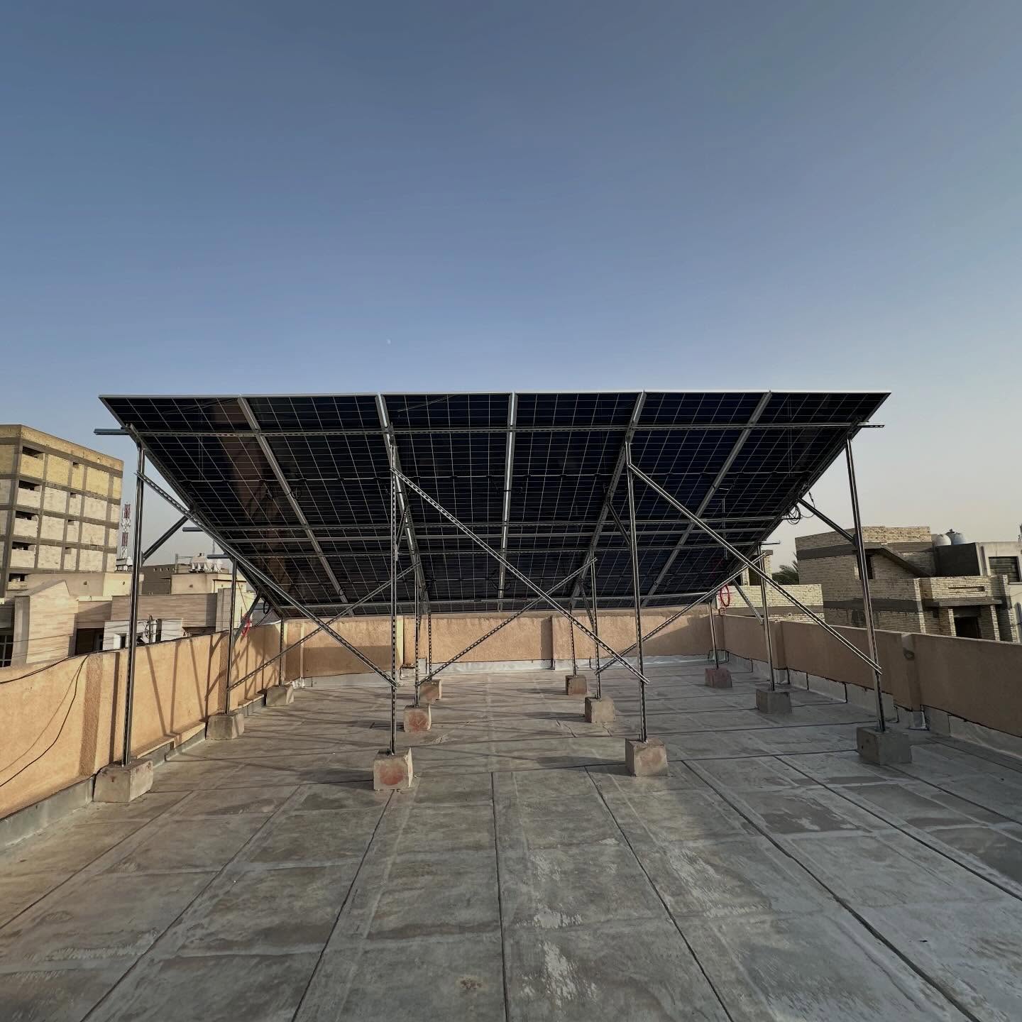 Elevated rooftop solar array of LONGi 625 W panels on a steel structure over a private building in Baghdad