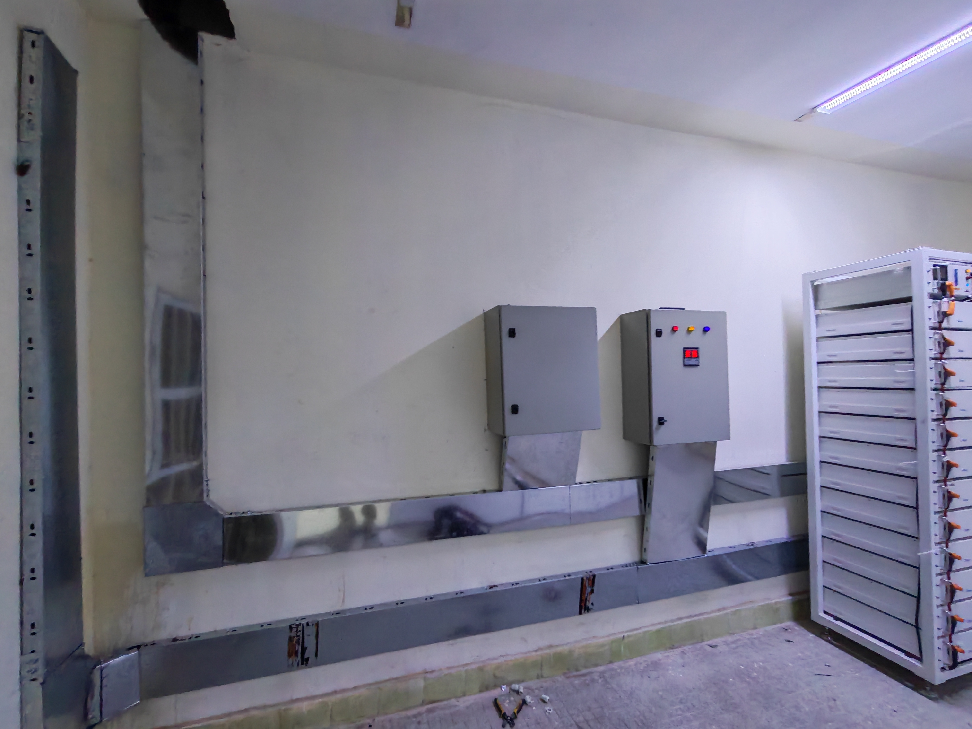 Battery storage racks and control cabinets inside the power room at the Al-Taji site